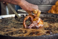 Hands in boiling oil indian chef fries fish with bare hands